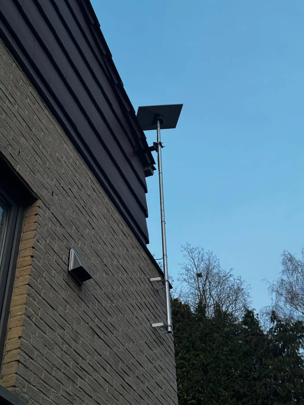 Antenne Starlink sur mât, façade en brique