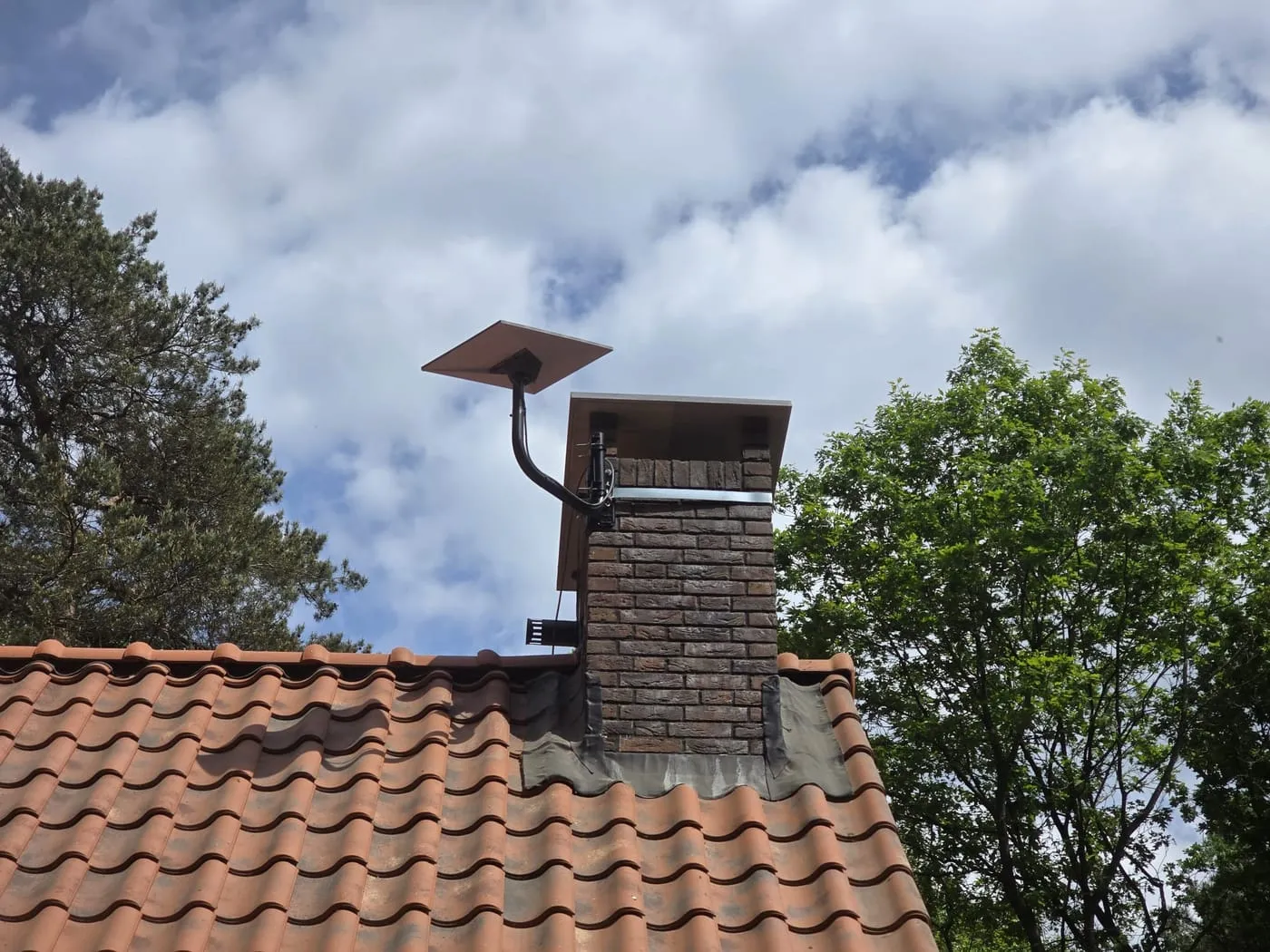 Antenne Starlink fixée à une cheminée, toit en tuiles