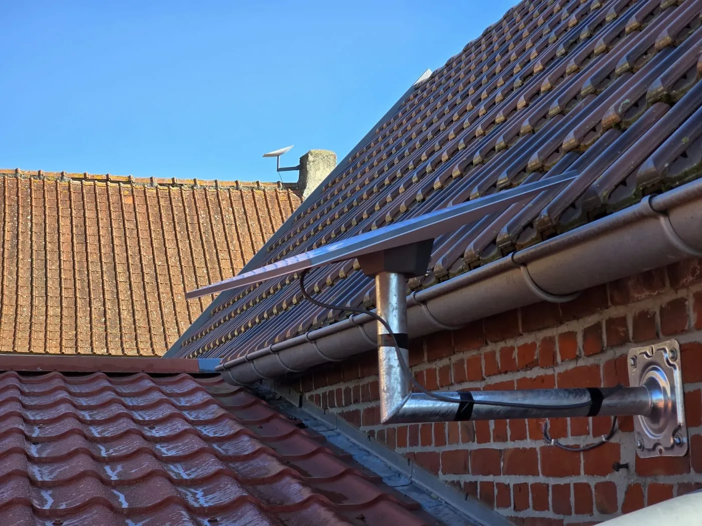 Antenne Starlink sur support mural, au-dessus d’un toit en tuiles