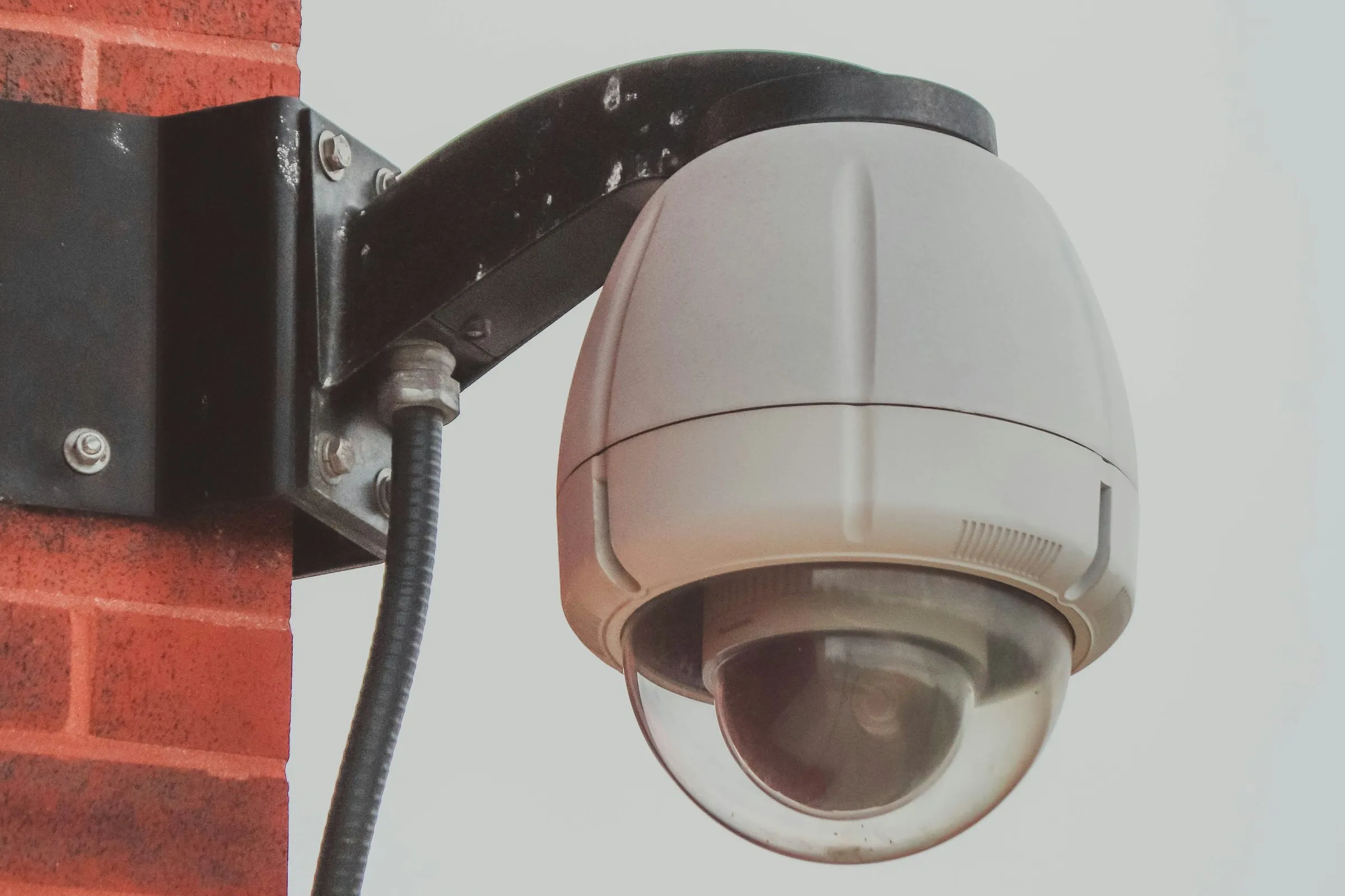 Caméra dôme blanche fixée sur un mur en briques