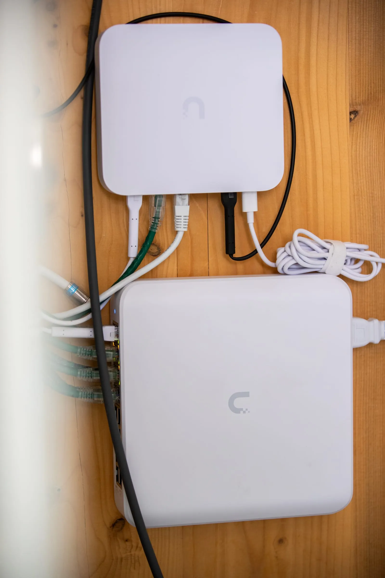 Équipements réseau UniFi fixés sur un panneau en bois, câbles raccordés