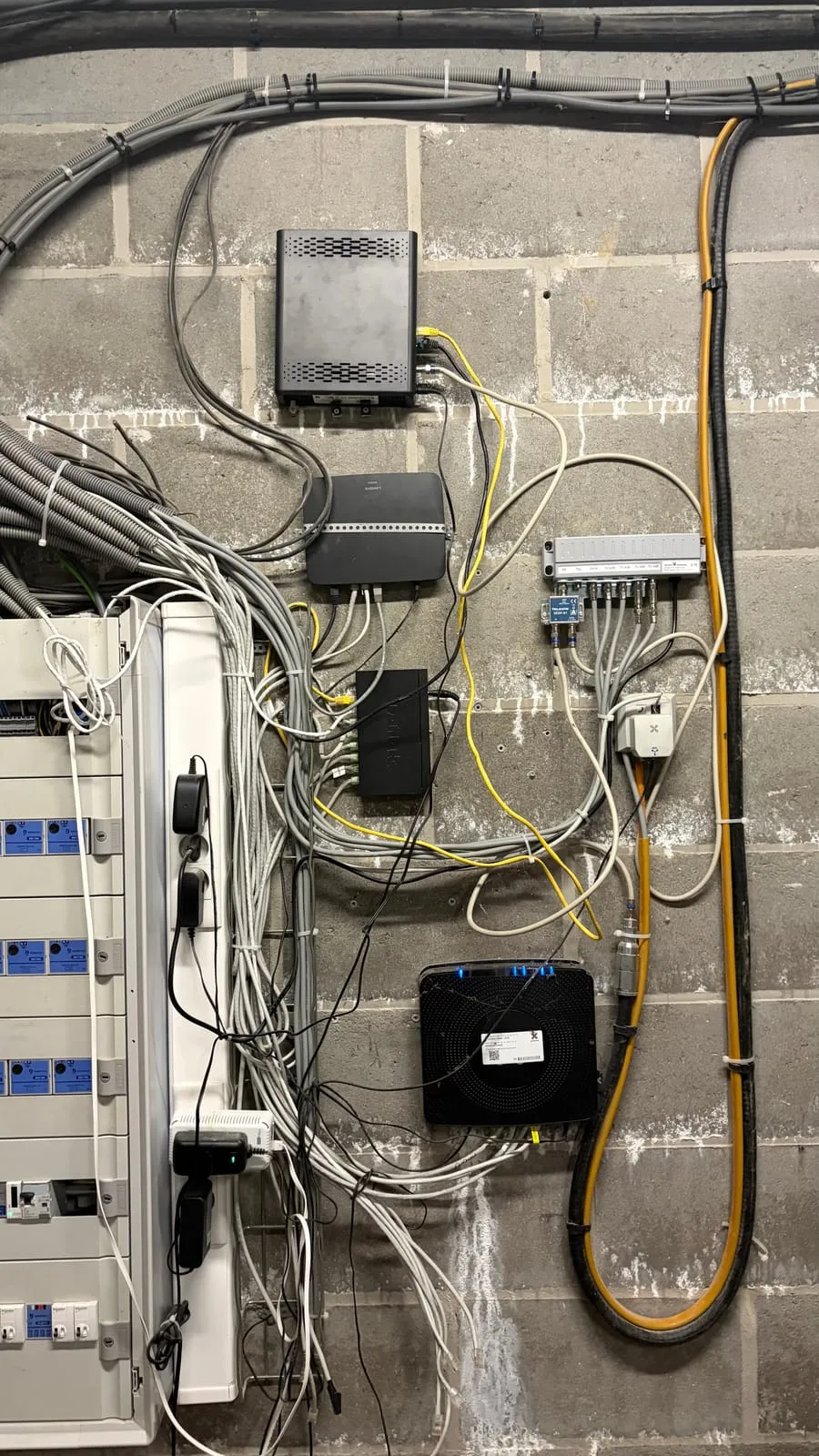 Local technique d'une entreprise avant l'intervention : câbles et boîtiers en désordre au mur