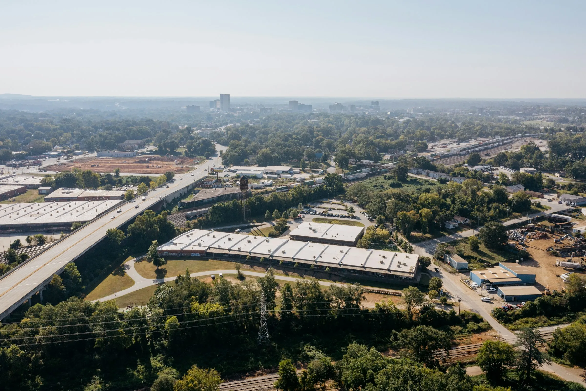 Vue aérienne de bâtiments d'entreprise et d'une route, entourés d'arbres