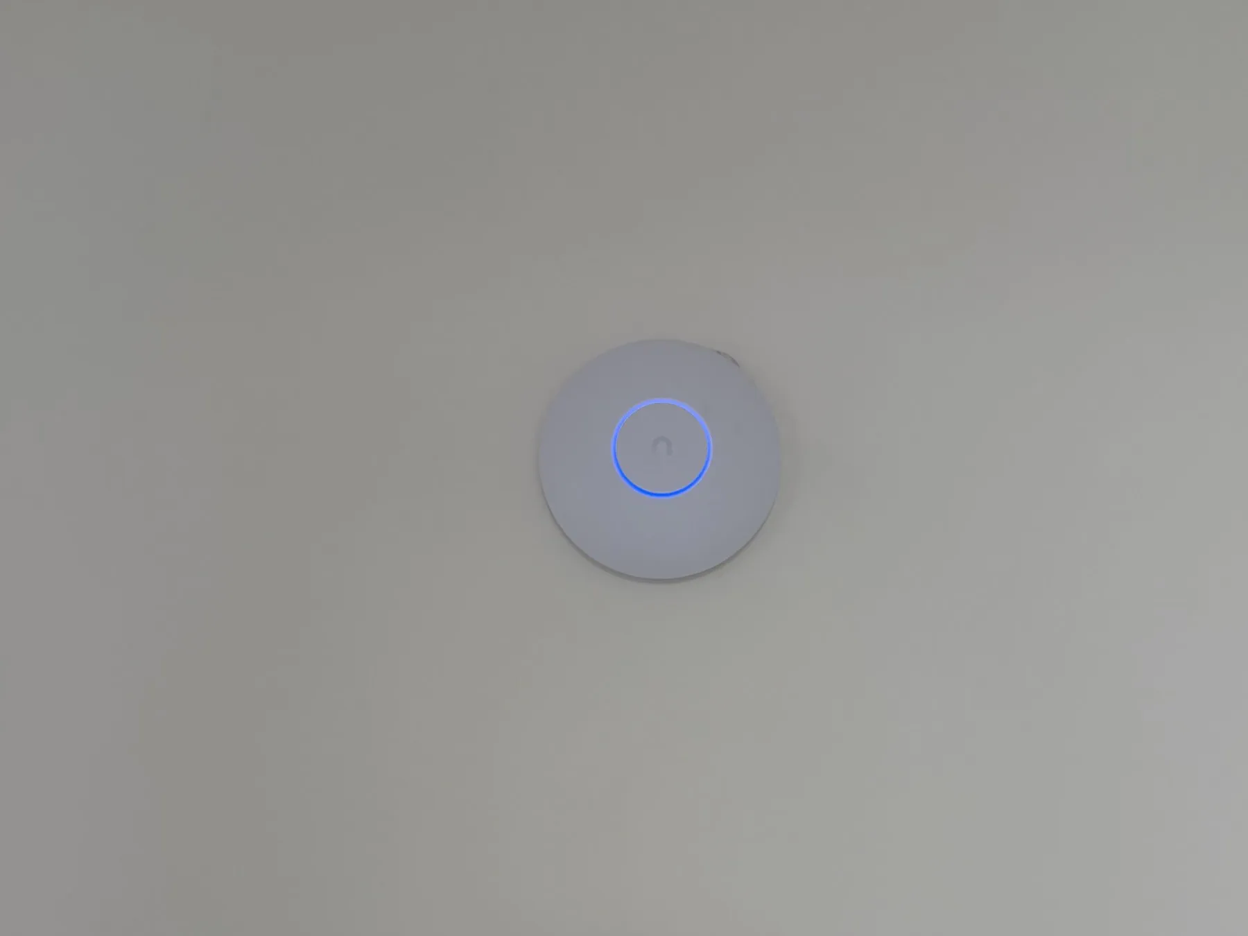 Borne Wi-Fi UniFi blanche fixée au mur, anneau lumineux bleu allumé