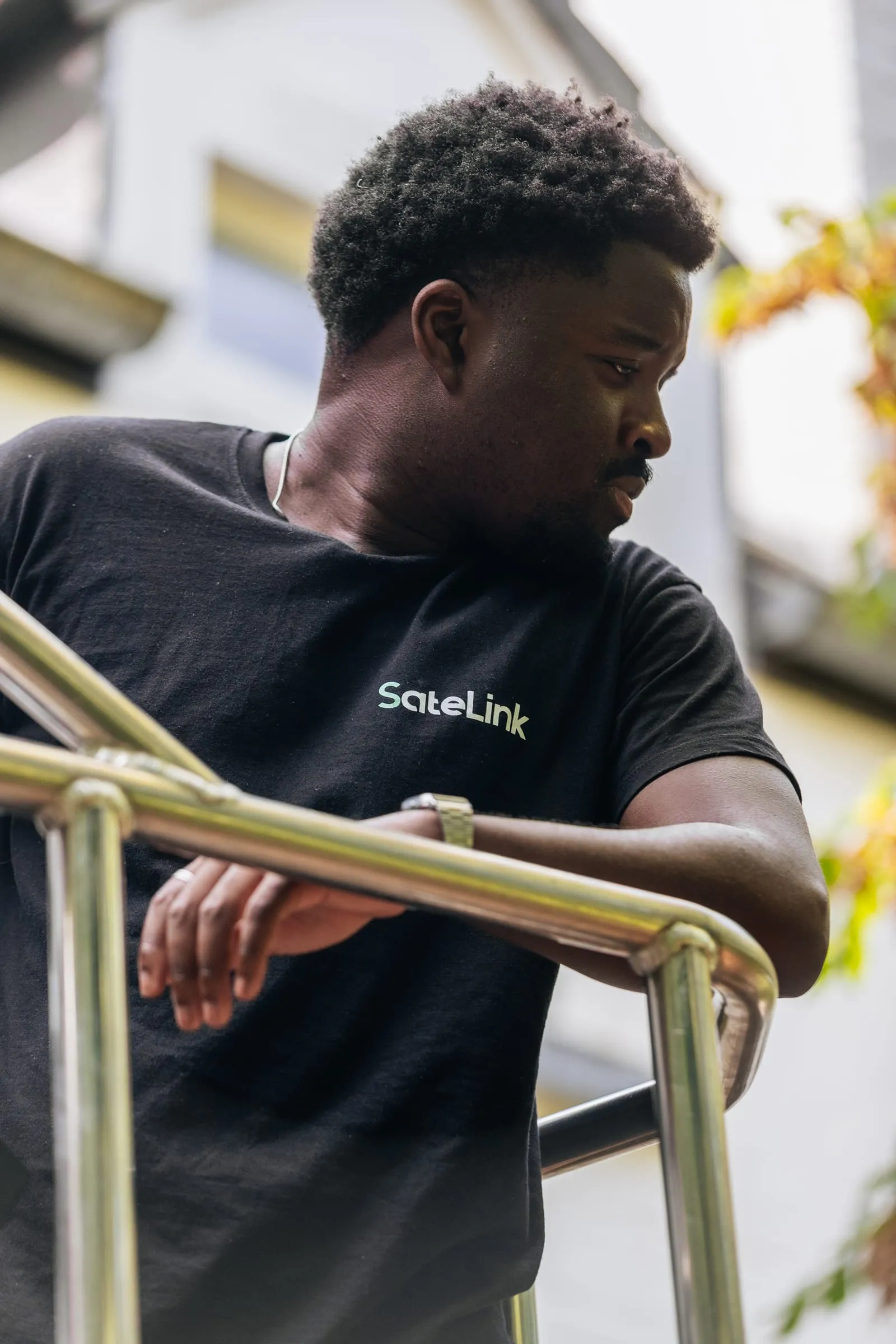 Romuald, en t-shirt SateLink, accoudé à une rambarde