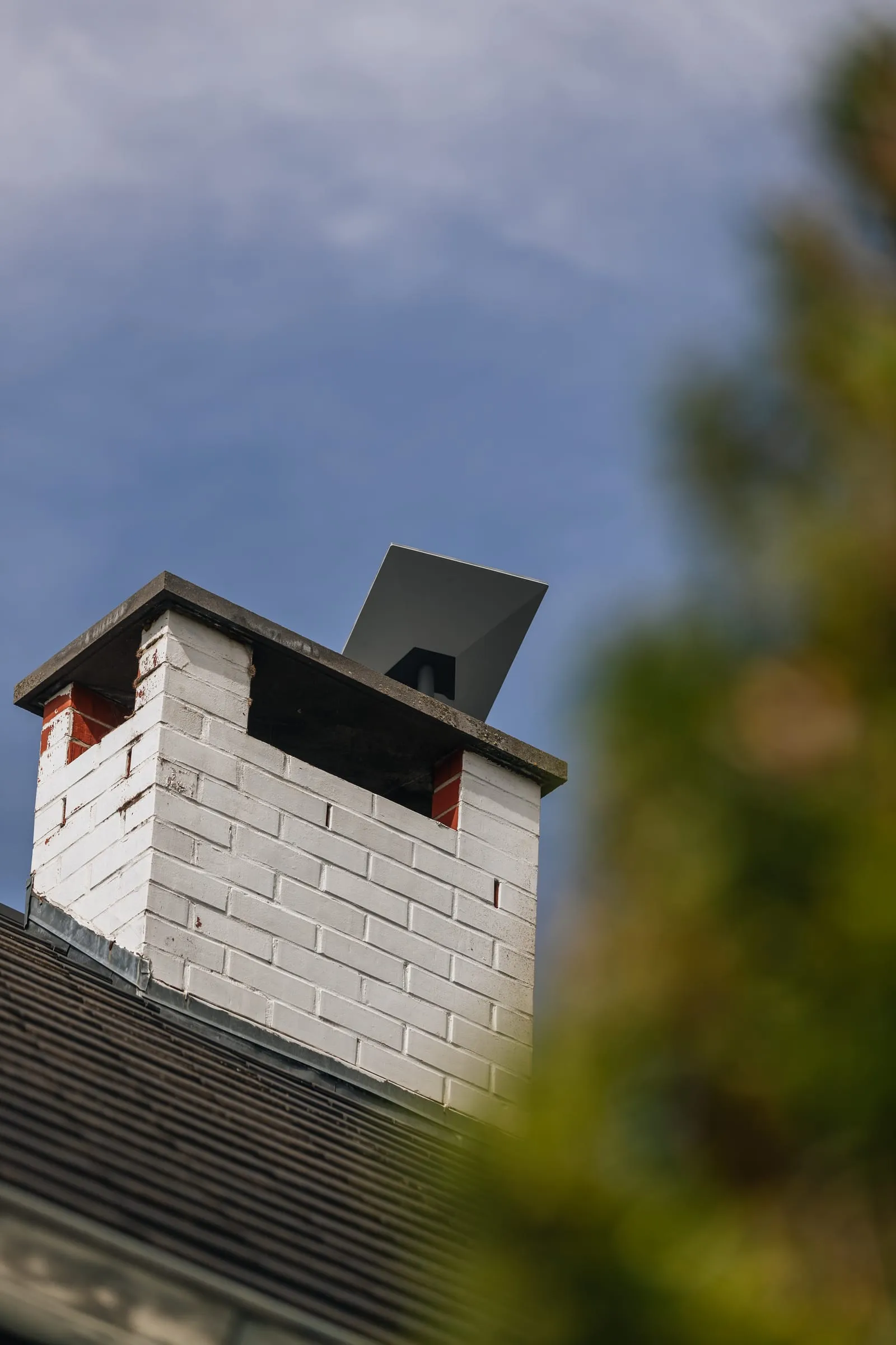 Antenne Starlink posée sur une cheminée en brique blanche, ciel bleu