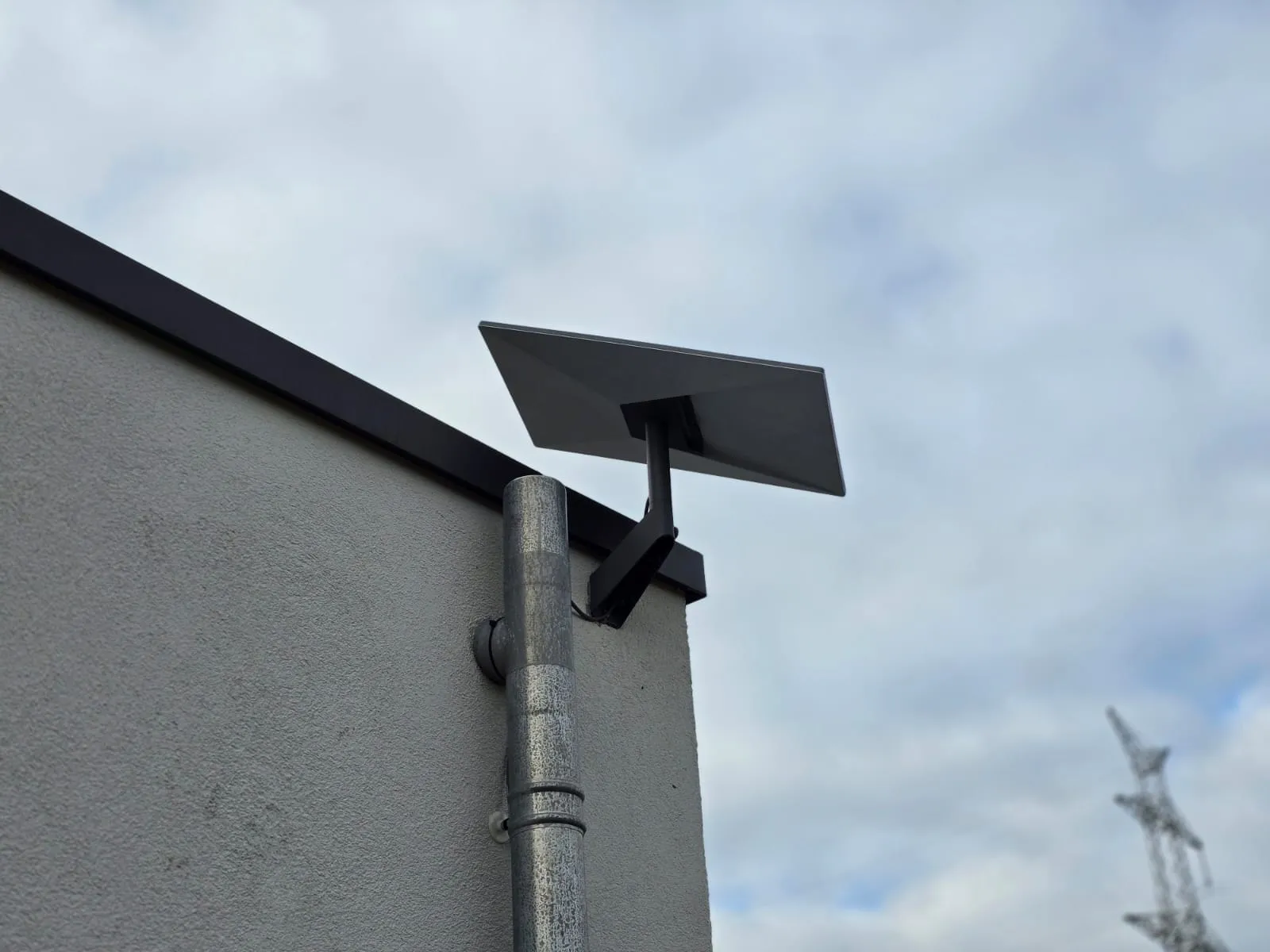 Antenne Starlink posée sur un support mural, contre un bâtiment d’entreprise